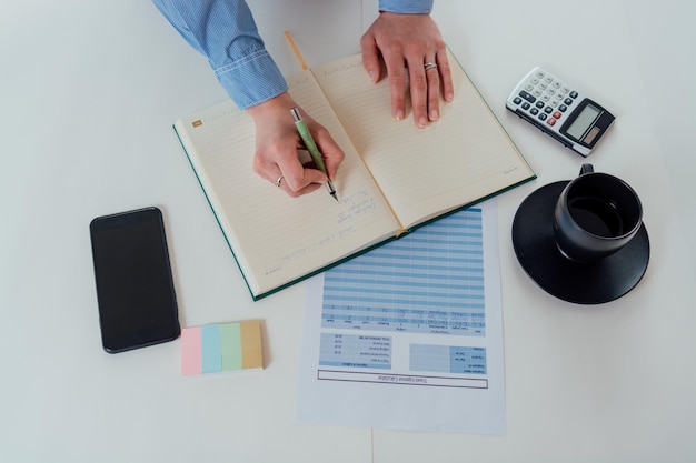 A person filling out an application form with a pen, with various documents like pay stubs and identification cards neatly arranged on the table.